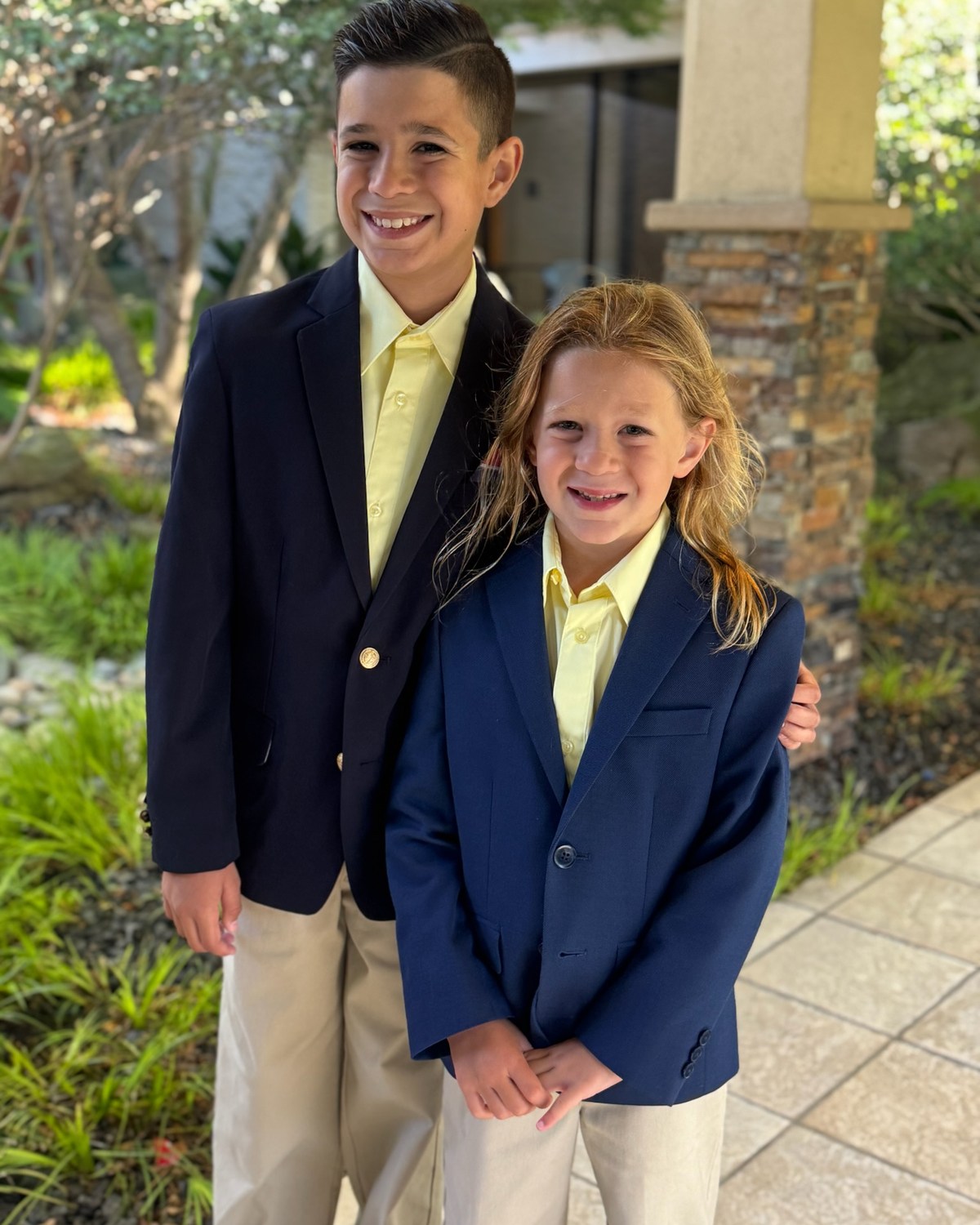 Two boys dressed in navy blazers and light trousers
