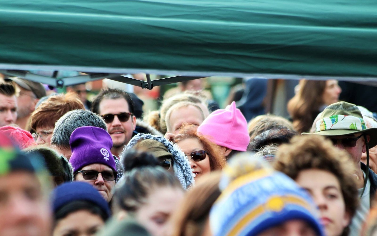 Crowd gathered at a civic march with several pink hats visible