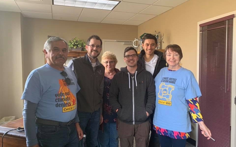 Six people gathered indoors wearing climate-action shirts