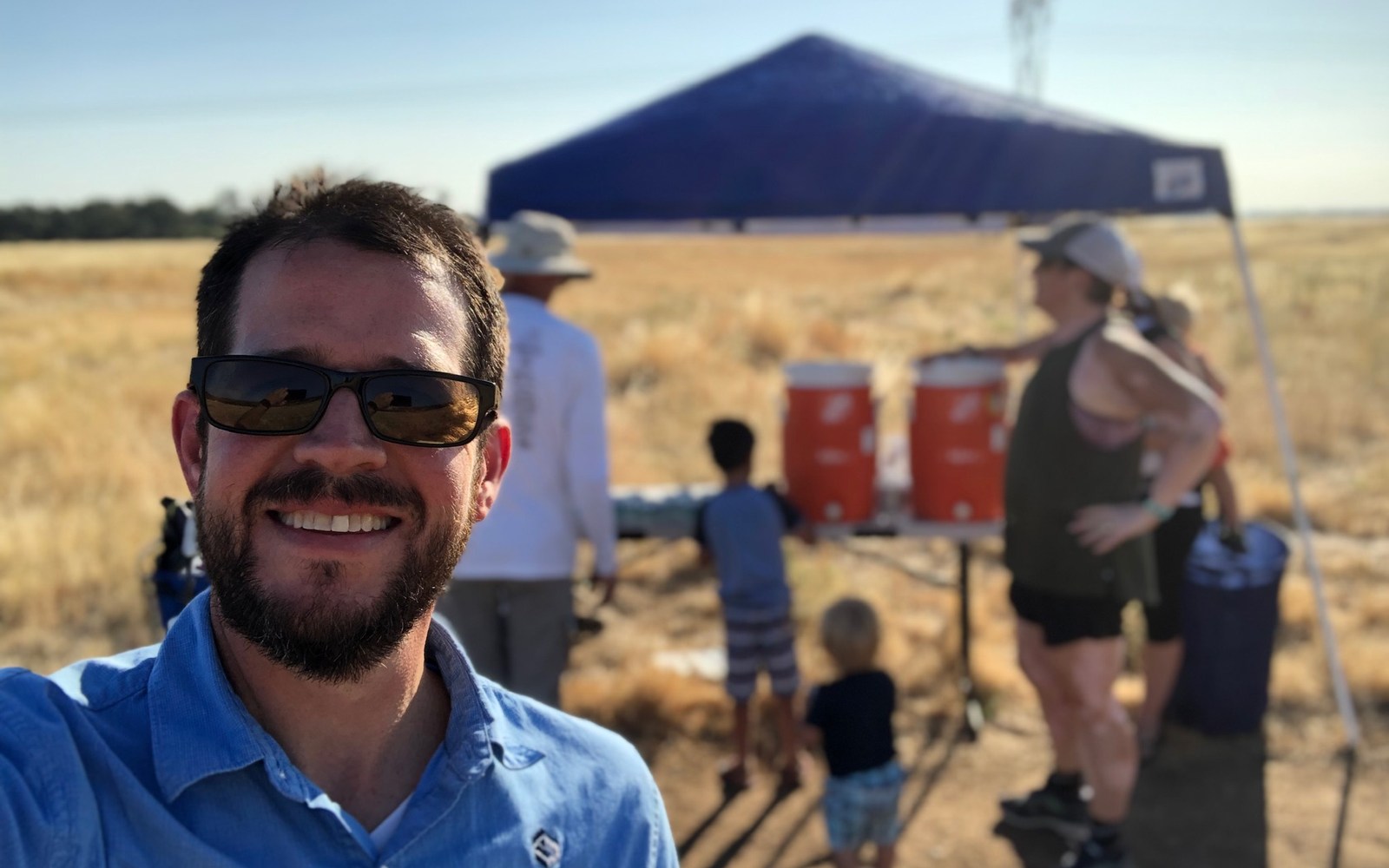 Volunteer at a shaded aid station in dry open country