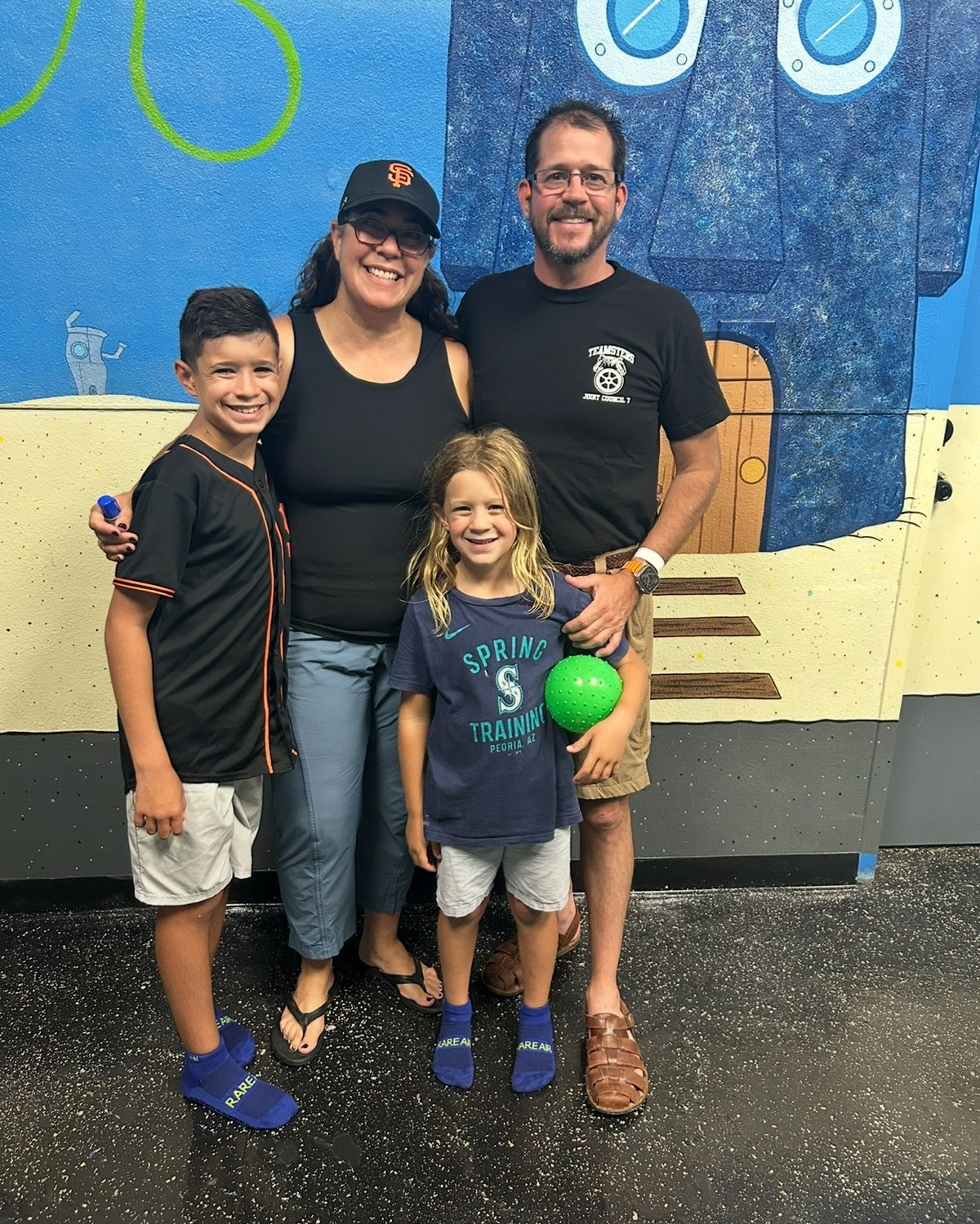Family of four standing together at an indoor recreation facility