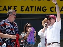 Contest participant raising one arm in celebration during a pancake-eating event