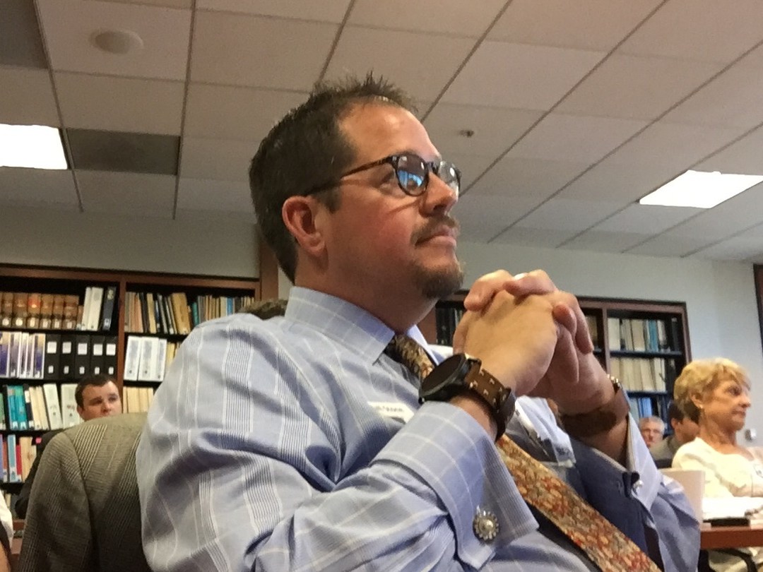 Randall Stone listening with hands clasped during a public-policy meeting