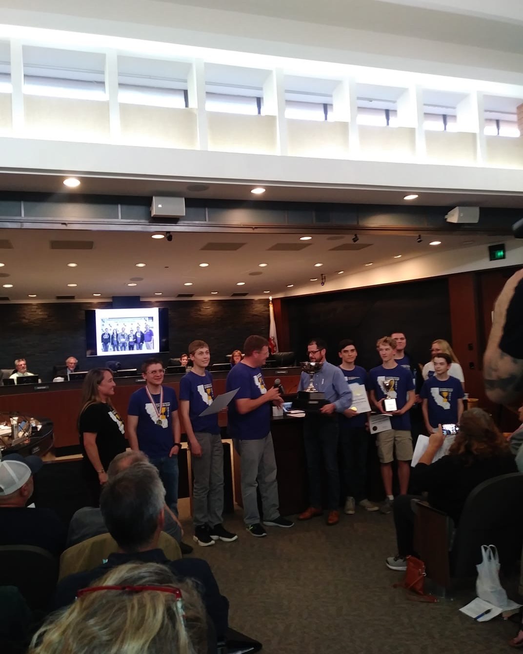 Student team receiving trophies and certificates in Chico City Council chambers