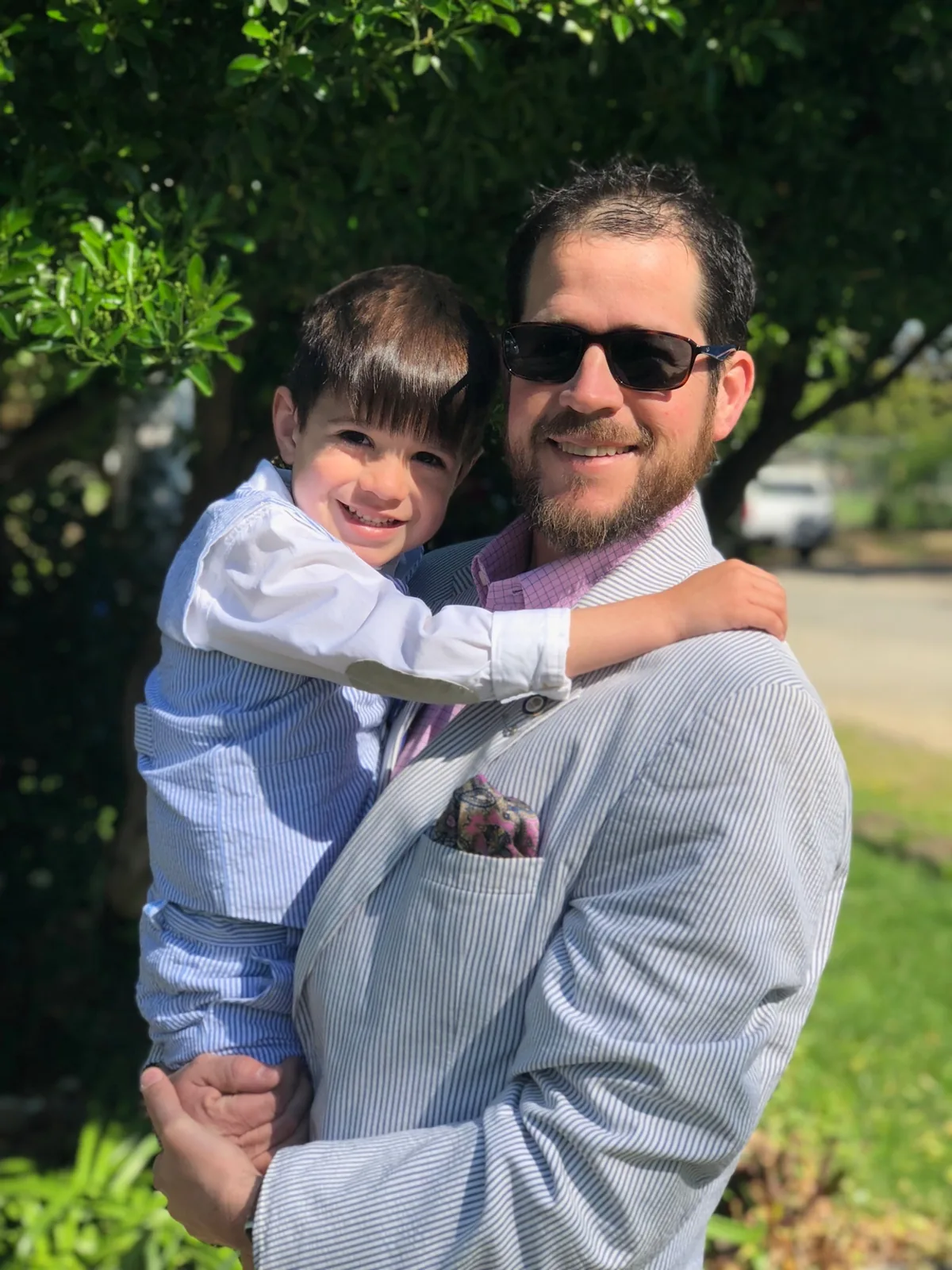 Randall Stone holding his young son outdoors in formal attire