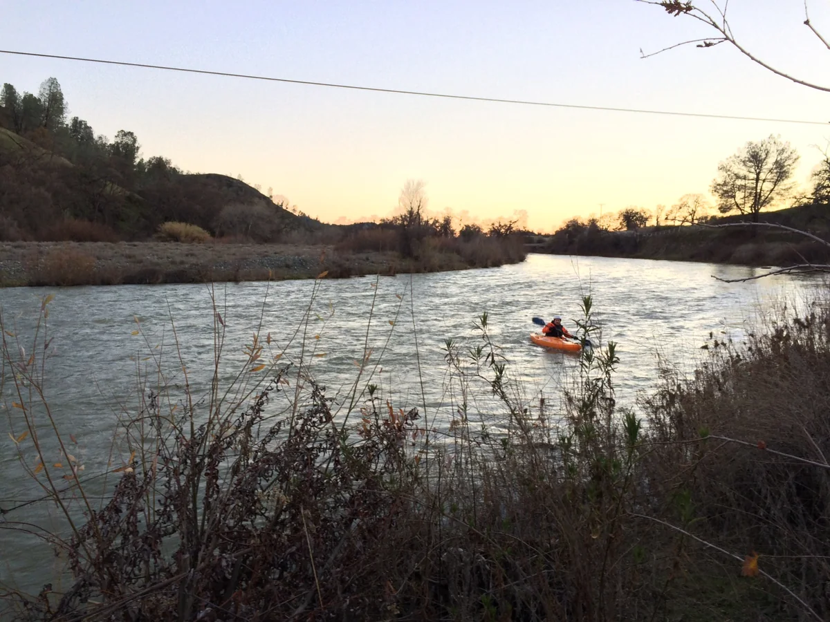 Randall Stone kayaking on a river near sunset