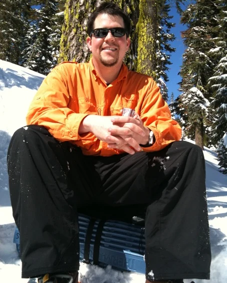 Randall Stone seated in deep snow during an earlier winter trip