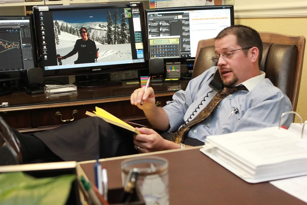 Randall Stone working at his office desk with multiple monitors and financial calculator