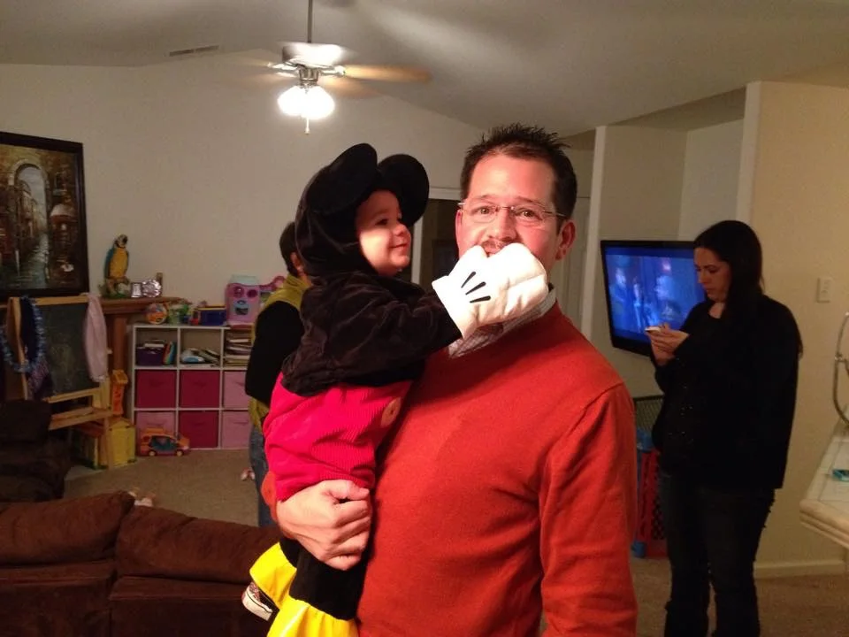 Rhys Stone dressed as Mickey Mouse playfully covering Randall Stone's mouth with a costume glove