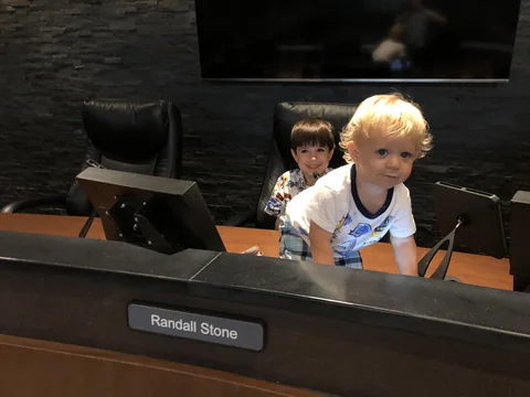 Two Stone children behind the Randall Stone nameplate at the City Council dais