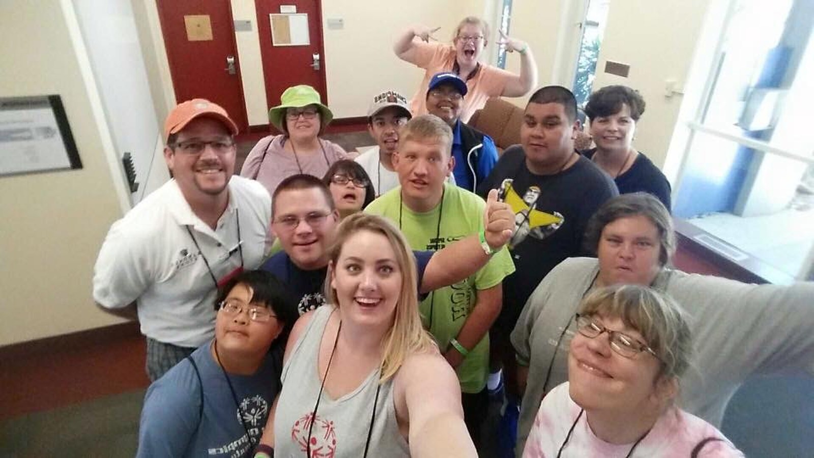 Special Olympics athletes, coaches, and volunteers gathered for a group selfie indoors